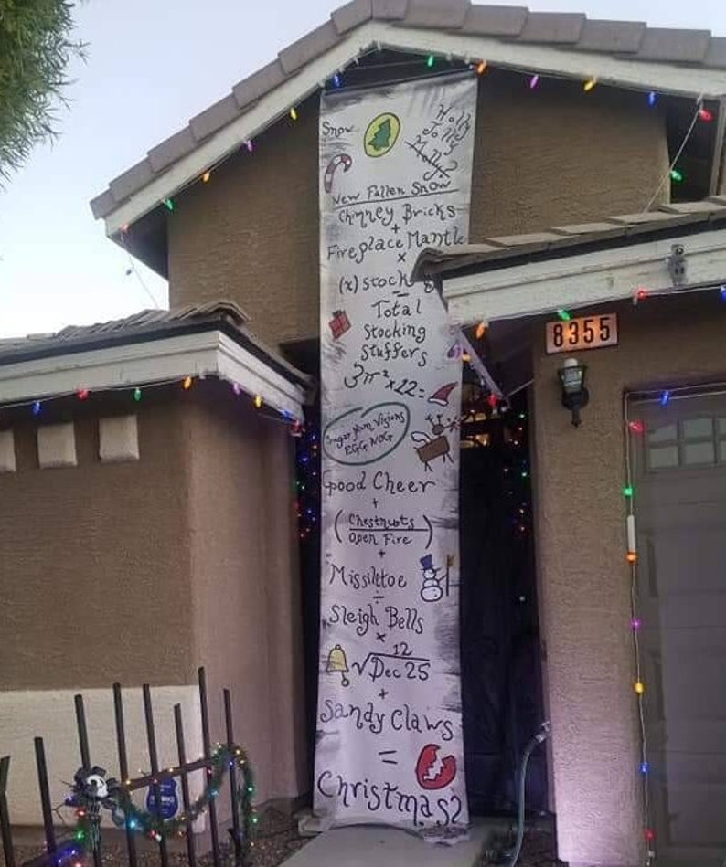 A house with a large Nightmare Before Christmas banner hanging from the roof, over the front door.