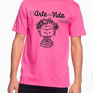 K&ouml;nnte beinhalten: Ein pinkfarbenes T-Shirt mit einer schwarzen Grafik von Frida Kahlo mit dem Text "El Arte es Vida - Frida Kahlo"