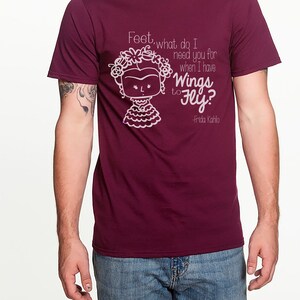 K&ouml;nnte beinhalten: Burgunderfarbenes T-Shirt mit einer wei&szlig;en Grafik von Frida Kahlo mit dem Zitat "F&uuml;&szlig;e, wozu brauche ich dich, wenn ich Fl&uuml;gel zum Fliegen habe? -Frida Kahlo"