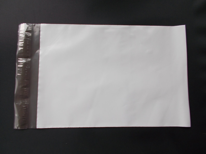 May include: A white poly mailer envelope with a self-sealing adhesive strip on the left side. The envelope is rectangular and appears to be empty. The background is a dark gray or black surface.