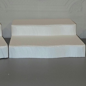 May include: Three white tiered display stands with rounded edges. The stands are made of a smooth, white material and are perfect for displaying small items.