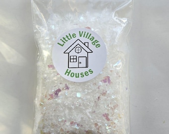 May include: A clear plastic bag filled with white iridescent glitter, labelled "Little Village Houses".
