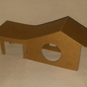 May include: A cardboard house with a rounded roof and a circular opening. The house is made of brown cardboard and has a simple design.