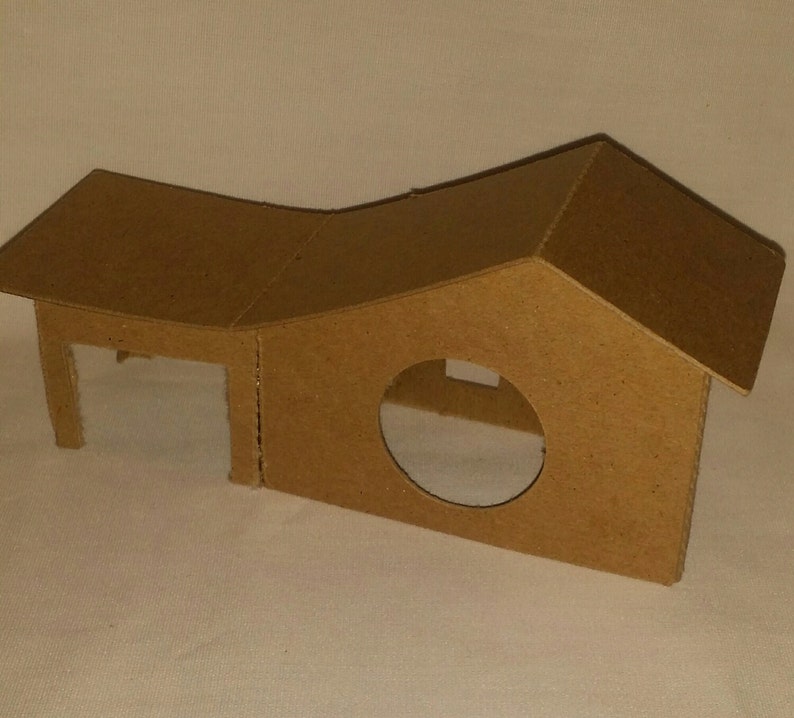 May include: A cardboard house with a rounded roof and a circular opening. The house is made of brown cardboard and has a simple design.