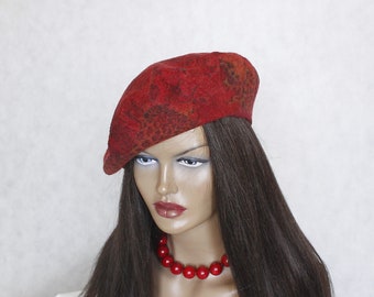 May include: A red beret with a brown and orange pattern. The beret is worn by a mannequin with long brown hair and a red beaded necklace.