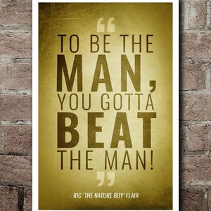 May include: A framed poster with a gold background and black text. The text reads "TO BE THE MAN, YOU GOTTA BEAT THE MAN!" and is attributed to Ric 'The Nature Boy' Flair. The poster is in a white frame.