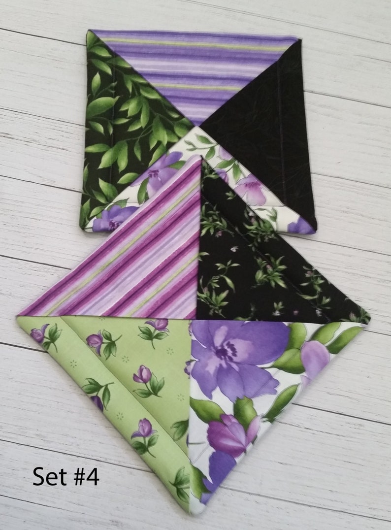 Puede incluir: Conjunto de dos agarraderas de olla de tela p&uacute;rpura, verde y negra con un patr&oacute;n floral. Las agarraderas tienen forma de diamante y est&aacute;n apiladas una encima de la otra. El texto "Set #4" es visible en la esquina inferior izquierda de la imagen.