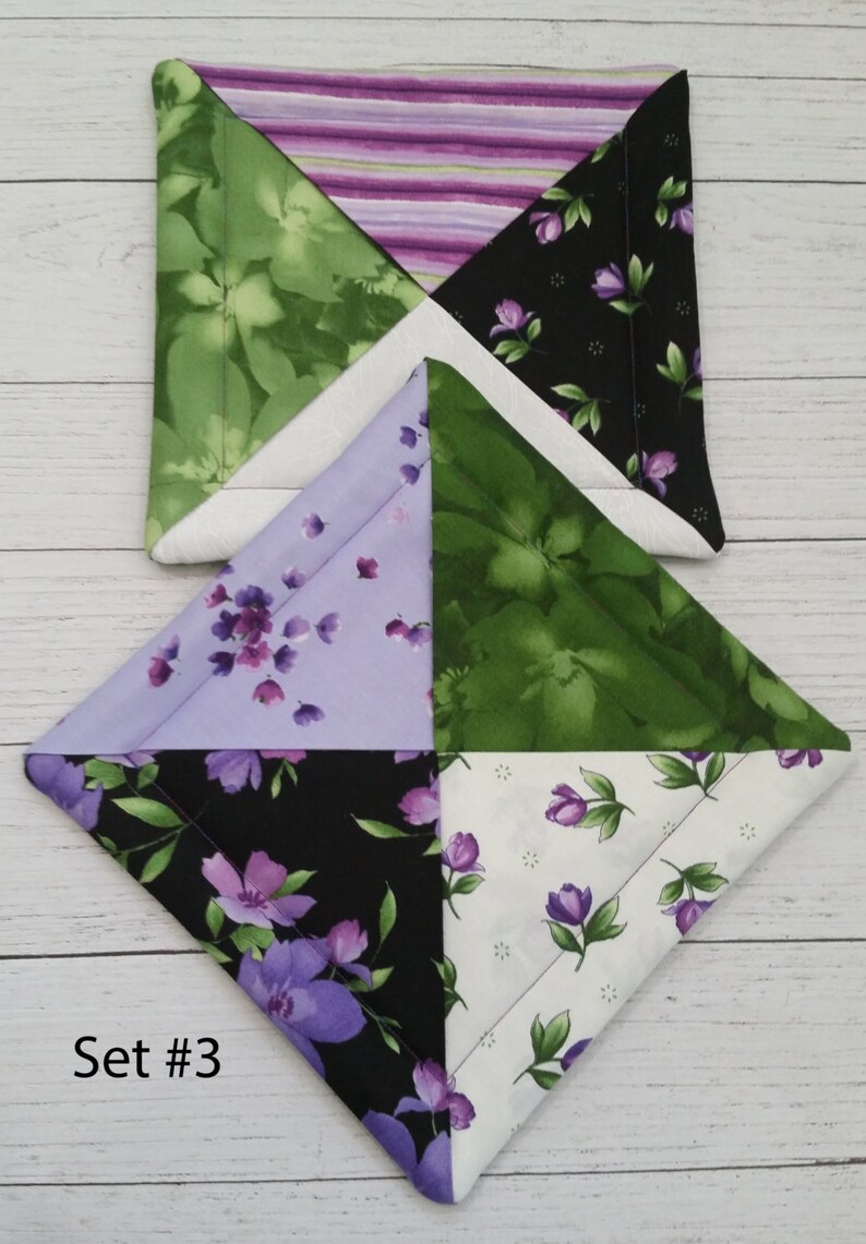 Puede incluir: Conjunto de dos agarraderas acolchadas con un dise&ntilde;o de patchwork. Las agarraderas presentan una variedad de patrones florales en tonos de verde, morado, blanco y negro. El texto "Set #3" es visible en la esquina inferior izquierda de la imagen.