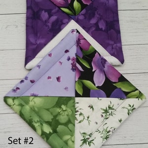 Puede incluir: Conjunto de dos posavasos de tela floral de color morado, verde y blanco. Los posavasos son cuadrados y tienen un dise&ntilde;o acolchado. El texto "Set #2" es visible en la esquina inferior izquierda de la imagen.