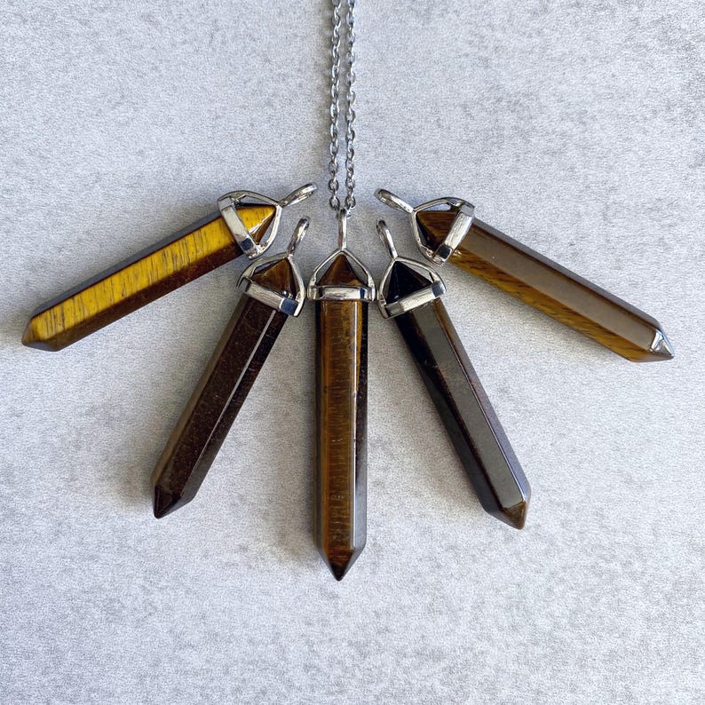 May include: Five gold tiger's eye crystal point pendants with silver caps hanging from a silver chain.