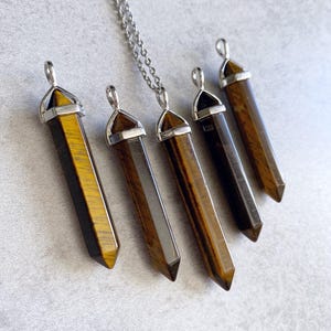 May include: Five gold and brown tiger's eye crystal point pendants with silver caps and a silver chain.
