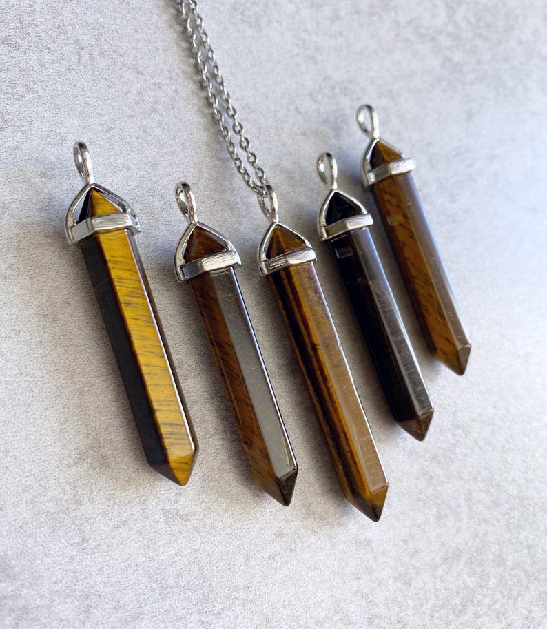 May include: Five gold and brown tiger's eye crystal point pendants with silver caps and a silver chain.