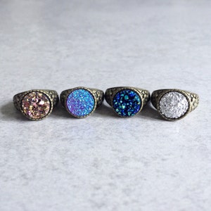Peut inclure: Quatre bagues avec des pierres d'agate de diff&eacute;rentes couleurs. Les bagues sont en laiton et ont une finition textur&eacute;e. Les pierres sont rose clair, bleu clair, bleu fonc&eacute; et blanche.