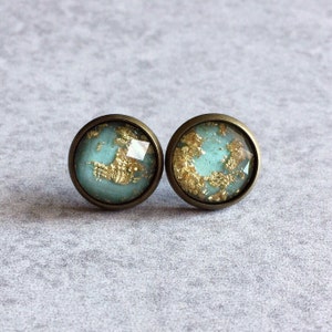 May include: A pair of gold and teal blue stud earrings with a bronze setting.