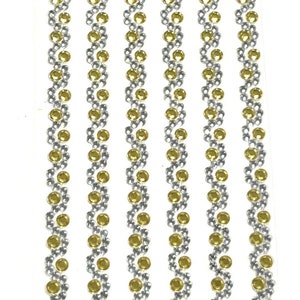 May include: Five strips of self-adhesive rhinestones with a silver and gold design. Each strip has a repeating pattern of silver and gold round rhinestones.