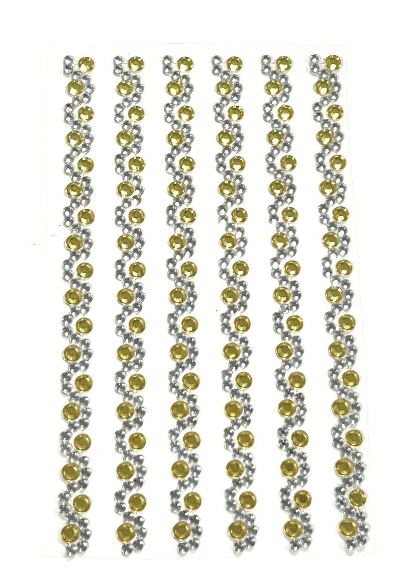 May include: Five strips of self-adhesive rhinestones with a silver and gold design. Each strip has a repeating pattern of silver and gold round rhinestones.