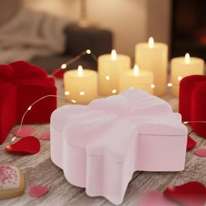 May include: A pale pink heart-shaped jewellery box on a wooden surface, with red heart-shaped boxes, lit candles, and rose petals. Fairy lights and heart-shaped biscuits complete the romantic scene.