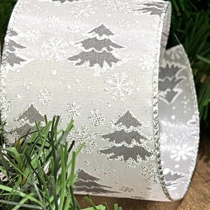 May include: White satin ribbon with a silver glitter finish and a repeating pattern of grey Christmas trees and snowflakes.