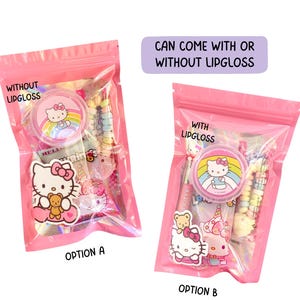May include: Two pink zip-lock bags, one labeled "WITHOUT LIPGLOSS" and the other "WITH LIPGLOSS". Each bag contains Hello Kitty themed items, including a lip balm, stickers, and candies. The text "CAN COME WITH OR WITHOUT LIPGLOSS" is also visible.