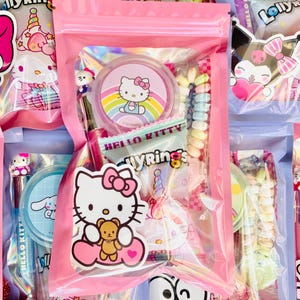 May include: Pink cellophane bags filled with colorful candies and Hello Kitty-themed stickers and accessories. The bags contain various candies, including rainbow-colored hard candies and lollipops. The image features multiple bags, creating a visually appealing display.