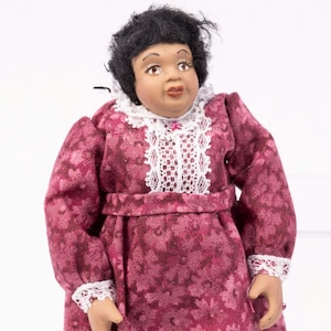 May include: A doll wearing a pink floral dress with white lace trim and black shoes.