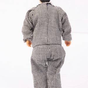 May include: A black and white checkered suit with a black jacket and pants. The suit is worn by a doll with black hair.