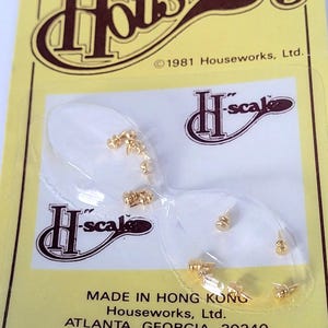 Könnte beinhalten: Eine gelbe Verpackung mit kleinen, goldfarbenen Miniatur-Hardware-Teilen, wahrscheinlich für den Modellbau. Die Verpackung ist mit "Houseworks" und "H-scale" beschriftet. Der Text enthält "MADE IN HONG KONG" und "ATLANTA, GEORGIA, 30340".