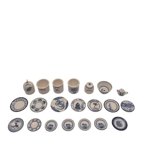 Może przedstawiać: Kolekcja miniaturowych niebiesko-białych porcelanowych naczyń i elementów do serwowania. Zestaw zawiera talerze, miski, filiżanki, imbryk i mały dzbanek. Wzory przedstawiają motywy kwiatowe i inne dekoracyjne.