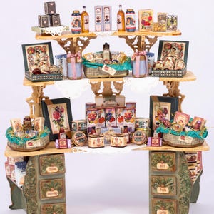 Puede incluir: Un mostrador de tienda de madera en miniatura con tres estantes llenos de tarros, botellas y cajas en miniatura de varios artículos de comida. El mostrador tiene cajones etiquetados como "Especias", "Condimentos", "Té", "Frutos secos", "Pasta" y "Café".