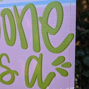 May include: A sign with the words "one is a" in large, lime green script. The background is light pink with a decorative floral pattern in pastel colors. The words "ham written" and "by Hannah Jones" are in the bottom right corner.