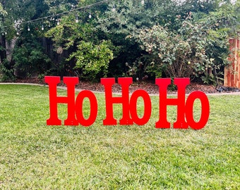 May include: Red wooden letters spelling "Ho Ho Ho" on a green grassy lawn.