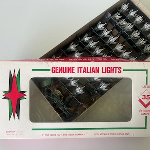 May include: A box of "GENUINE ITALIAN LIGHTS" with 35 Philips lamps. The box is white with a red and green starburst design. The lights are white and arranged in a grid.