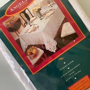 May include: White tablecloth with colour embroidery and hand cutwork. The tablecloth is 163 cm by 213 cm and includes eight napkins. The tablecloth is shown on a table with a centrepiece of fruit and flowers.