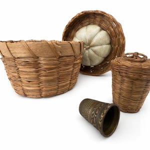 May include: An assortment of woven baskets and a thimble. The baskets vary in size and shape, with one having a lid and another a white padded interior. The thimble is bronze-colored with an ornate floral design.