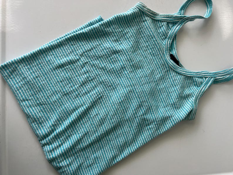 Puede incluir: Camiseta sin mangas a rayas turquesa y blancas con tirantes finos. La parte superior est&aacute; hecha de una tela suave y acanalada. Los tirantes son de un tono m&aacute;s claro de turquesa y blanco.