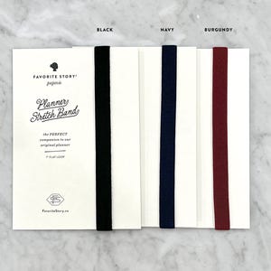 K&ouml;nnte beinhalten: Produktfoto von Planer-Gummib&auml;ndern in Schwarz, Marineblau und Burgunderrot. Jedes Band ist an einer wei&szlig;en Karte mit dem Text "Planner Stretch Band" und "7" flat loop befestigt. Der Markenname "Favorite Story" ist ebenfalls sichtbar.