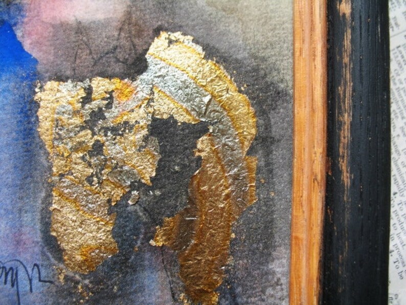 May include: Abstract art painting with gold and silver leaf accents on a dark background. The painting is framed in a black and wood frame.