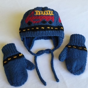 May include: Blue knitted hat and mittens set with a red truck design. The hat has a long tie and the mittens have a black and yellow trim.