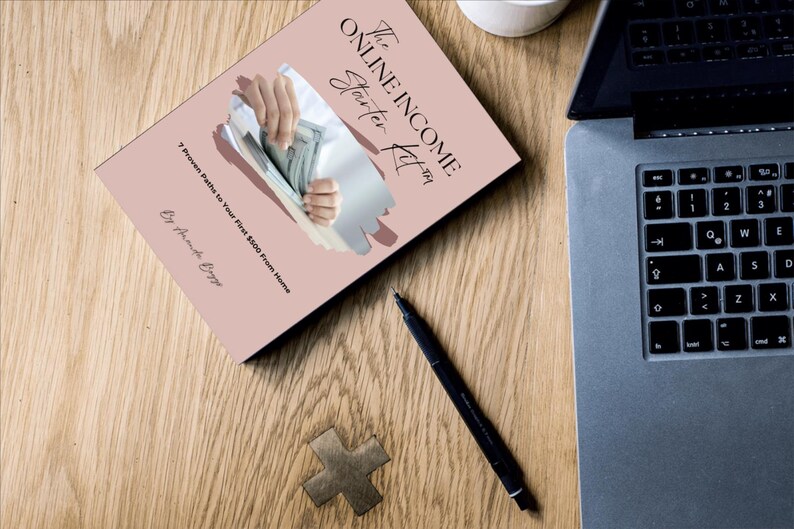 May include: A book titled "The Online Income Starter Kit" with the subtitle "7 Proven Paths to Your First $500 From Home" is displayed on a wooden surface. A laptop, pen, and decorative wooden cross are also visible.