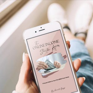 May include: A white smartphone displays a screen with the text "The Online Income Starter Kit" and an image of hands holding money. The phone is held by a person wearing blue jeans. The text below reads "7 Proven Paths to Your First $100 From Home."