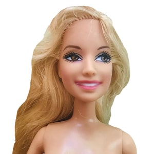 Könnte beinhalten: Eine Puppe mit langen, blonden Haaren und einem lächelnden Gesicht. Die Puppe hat braune Augen mit langen Wimpern und trägt hellrosa Lippenstift. Der Hautton der Puppe ist hell, und der Hintergrund ist weiß.