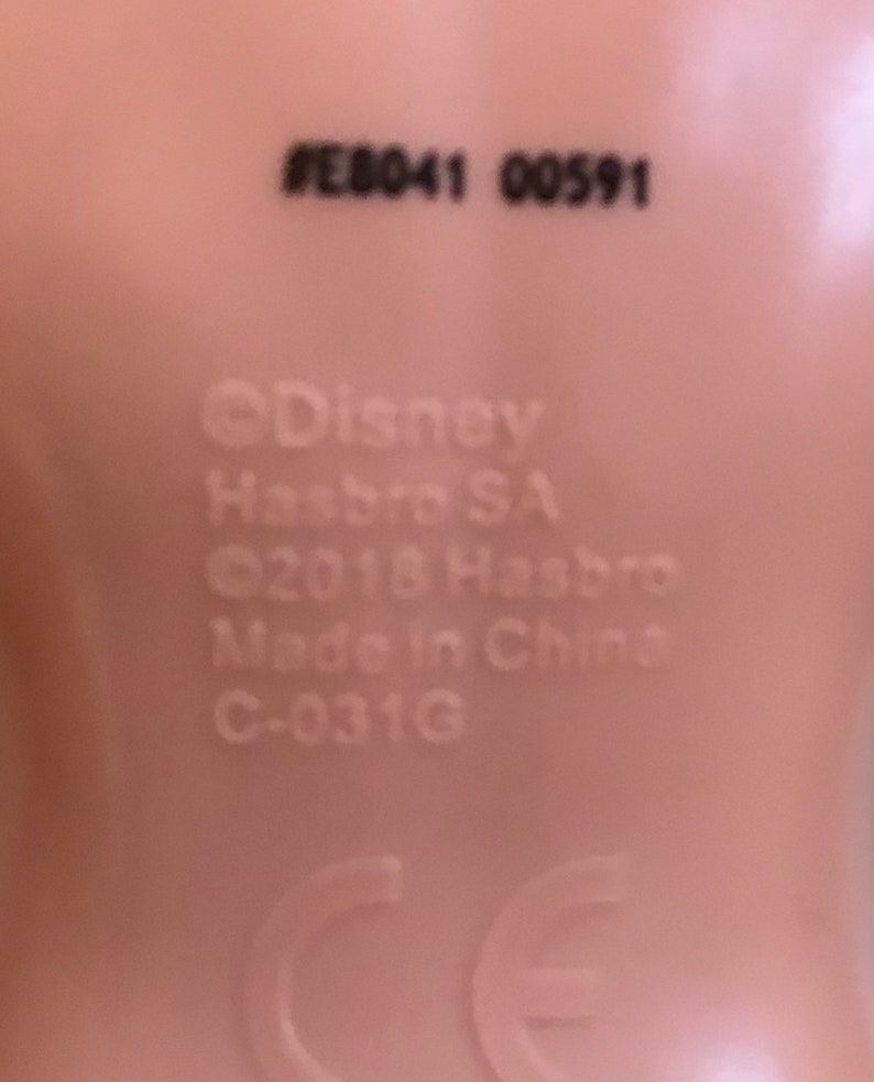 May include: Close-up of a doll's foot with the text #E8041 00591, &copy;Disney Hasbro SA, &copy;2018 Hasbro, Made in China, C-031G, and a CE mark.