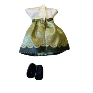 May include: A green and gold dress with a white bodice and a black trim. The dress has a glittery texture and a floral design. The dress is paired with black shoes.