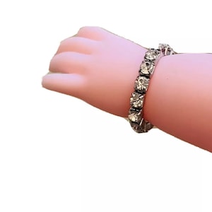 Puede incluir: Un brazalete plateado con diamantes de imitación transparentes.