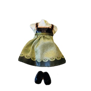 May include: A green and black dress with a white bodice and a glittery skirt. The dress has a black belt and a green and white floral pattern. The dress is paired with black shoes.