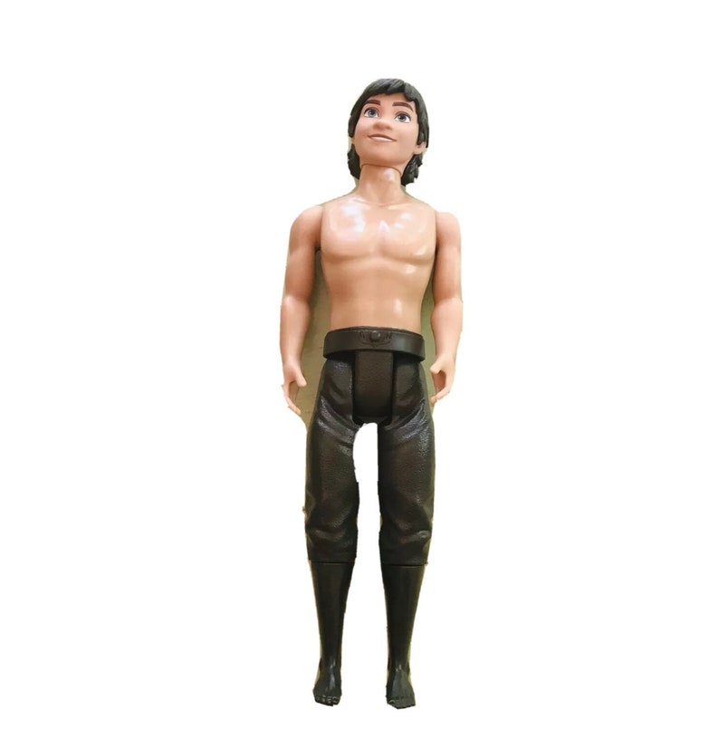 Puede incluir: Una mu&ntilde;eca de pl&aacute;stico con cabello casta&ntilde;o y un atuendo de cuero marr&oacute;n. La mu&ntilde;eca lleva un cintur&oacute;n y botas.