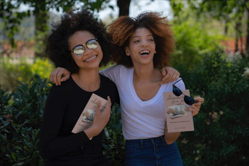 May include: Two smiling people, one in a black long-sleeve shirt and the other in a white V-neck, hold books with the title "The Online Incubation Guide". Both wear sunglasses. The background is a blurred outdoor scene.