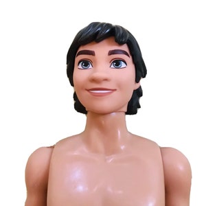 Puede incluir: Una mu&ntilde;eca de pl&aacute;stico con tez morena, cabello negro y ojos marrones. La mu&ntilde;eca sonr&iacute;e y tiene el torso desnudo.