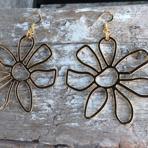 May include: A pair of gold-tone earrings shaped like stylised flowers. The earrings have a simple, modern design.