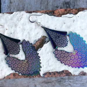 May include: A pair of iridescent black dangle earrings with a geometric design. The earrings are made of metal and have a delicate, intricate pattern.